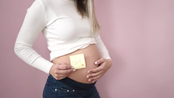 Jong Zwanger Vrouw Zetten Meisje Herinnering Papier Buik Geïsoleerde Roze — Stockvideo