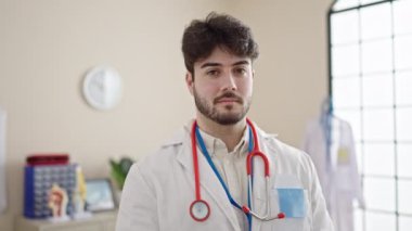 Genç İspanyol doktor gülümsüyor klinikte elleriyle kalp hareketi yapıyor.