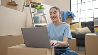 Genç, güzel, İspanyol bir kadın yeni evinde elinde anahtarlarla görüntülü arama yapıyor.