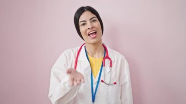 Genç, güzel, İspanyol kadın doktor gülümseyen, kendine güvenen, pembe arka planda öpüşen.