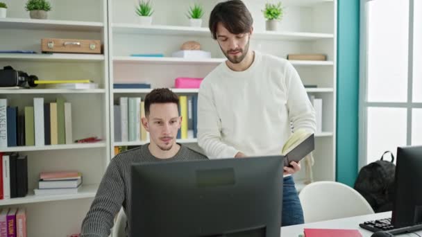 図書館大学で学ぶコンピューター リーディング ブックを使っている2人の男性 — ストック動画