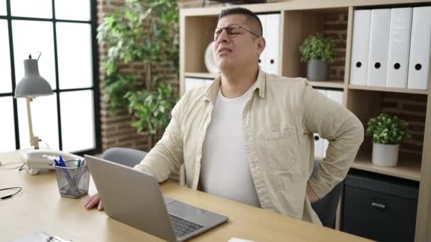 若いヒスパニック系のサラリーマンが事務所で腰痛に苦しんでいます — ストック動画