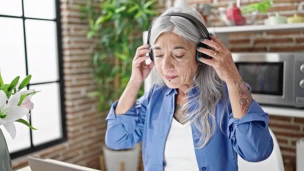 Średniowieczna Siwowłosa Kobieta Korzystająca Laptopa Wyjmująca Słuchawki Relaksujące Jadalni — Wideo stockowe