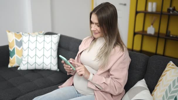 Genç Hamile Kadın Akıllı Telefon Kullanıyor Evde Karnına Dokunuyor — Stok video