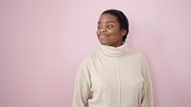 アフリカ系アメリカ人の女性がピンクの背景の向こうを指差して笑っている — ストック動画