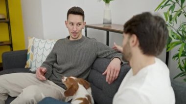 Kanepede oturan ve evde konuşan iki erkek.