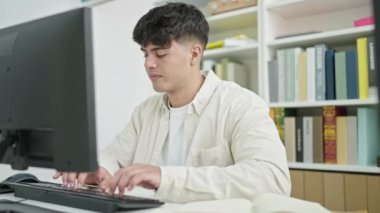 Genç İspanyol öğrenci kütüphane üniversitesinde bilgisayar notu kullanıyor.