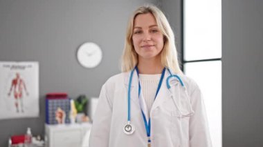 Klinikte kendine gülen genç sarışın kadın doktor.