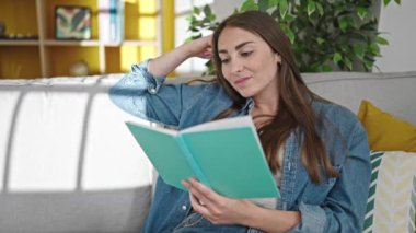 Evdeki kanepede oturmuş kitap okuyan güzel İspanyol kadın.