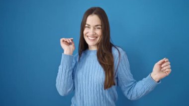 Kafkasyalı genç bir kadın gülümsüyor mavi arka planda dans ediyor.