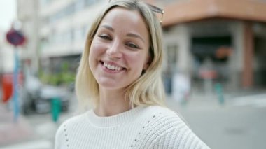 Sokakta kendine güvenen genç sarışın kadın gülümsüyor