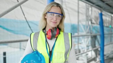 Sarışın genç bir mimar gülümsüyor.