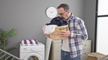 Orta yaşlı adam gülümsüyor. Çamaşır odasında kendine güveni olan sepet gibi kokan adam.