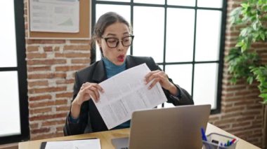 Genç, güzel, İspanyol bir iş kadını ofiste kâğıt atarak dans ediyor.