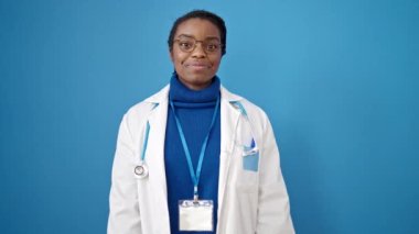 Afrikalı Amerikalı kadın doktor, izole edilmiş mavi arka planda sessizlik istiyor.