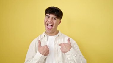 Genç İspanyol gülümseyen adam kendini izole edilmiş sarı arka planda göstererek kendine güveniyor.