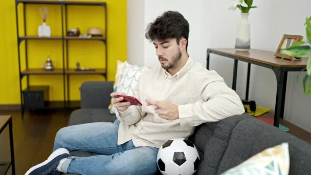 Jonge Spaanse Man Kijken Naar Voetbalwedstrijd Smartphone Kruisen Vingers Thuis — Stockvideo
