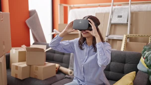 年轻美丽的惊慌失措的女人 戴着虚拟现实的眼镜 坐在新家的沙发上 — 图库视频影像