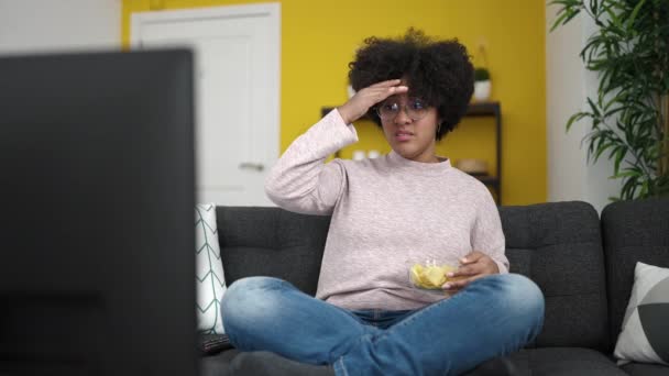 Joven Afroamericana Mujer Viendo Televisión Sentado Sofá Comiendo Patatas Fritas — Vídeo de stock