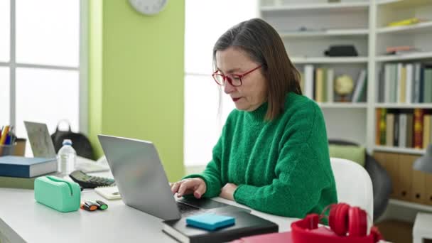 在图书馆使用带有背痛的笔记本电脑学习灰色头发的成熟的恐慌女人 — 图库视频影像