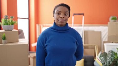 Afro-Amerikalı kadın gülümsüyor. Yeni evin anahtarlarını tutuyor.