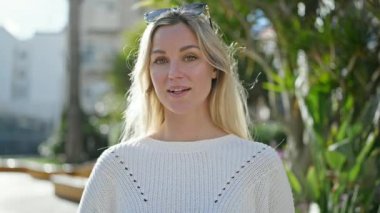 Young blonde woman smiling confident speaking at park