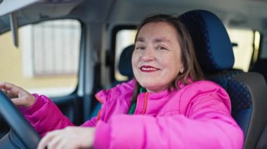 Yaşlı, beyaz saçlı, kendine güveni tam bir İspanyol kadın sokakta arabada oturuyor.