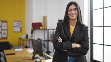 Genç, güzel, İspanyol bir iş kadını ofiste kendinden emin gülümsüyor.