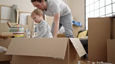 Baba ve oğul yeni evlerinde köpük karton kutuyla oynuyorlar.