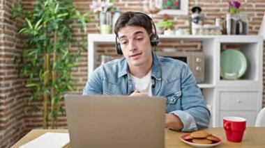 Genç İspanyol adam yemek odasında online ders alıyor.