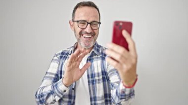 Orta yaşlı bir adam izole edilmiş beyaz bir arkaplanda video araması yaptığından emin gülümsüyor.