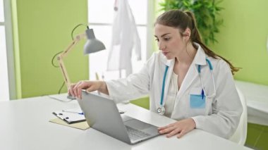 Genç, güzel İspanyol kadın doktor klinikte laptopunu kullanıyor.