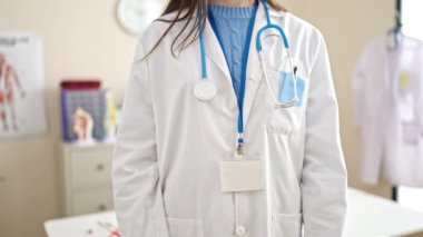 Genç beyaz kadın doktor klinikte dur işareti yapıyor.