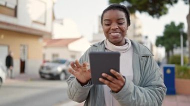 African american woman smiling confident using touchpad at street