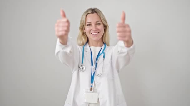 年轻的金发女医生用大拇指捂住孤立的白色背景 — 图库视频影像