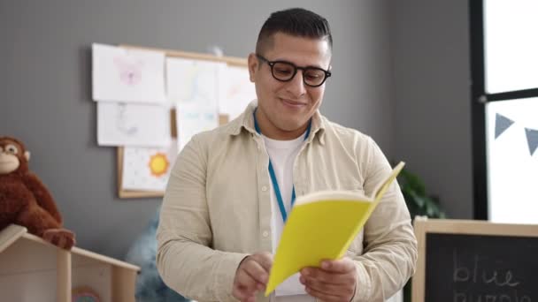 Young Hispanic Man Preschool Teacher Reading Book Standing Kindergarten — Stock video