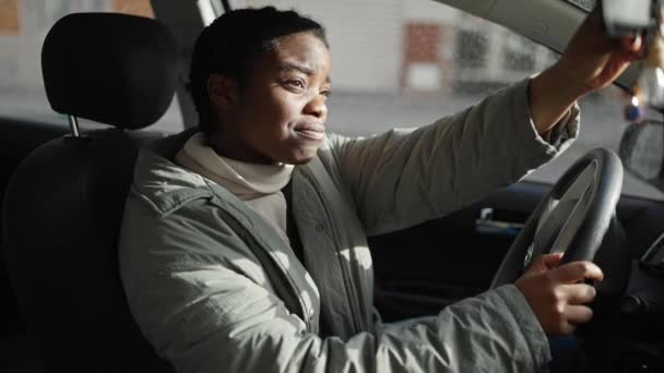坐在街上的汽车上触摸后视镜的非裔美国妇女 — 图库视频影像