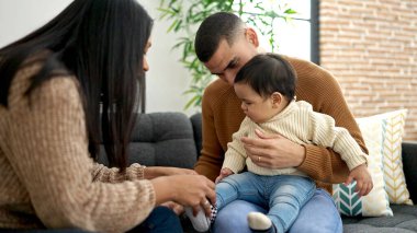 Çift ve oğul evdeki kanepede oturup birbirlerine sarılıyorlar.