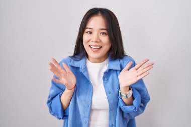 Beyaz arka planda duran genç Çinli kadın çılgın ve başarıyı kollarını kaldırıp heyecanla haykırarak kutluyor. Kazanan konsept 