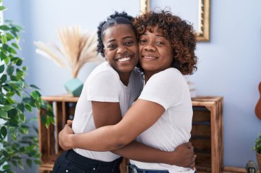 African american women mother and daughter hugging each other at home