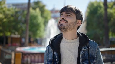 Young hispanic man smiling confident at park