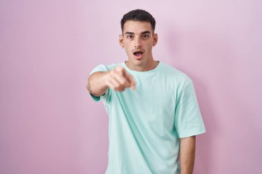 Yakışıklı İspanyol bir adam pembe arka planda dikiliyor. Kameraya kızgın ve sinirli olduğunu gösteriyor. 