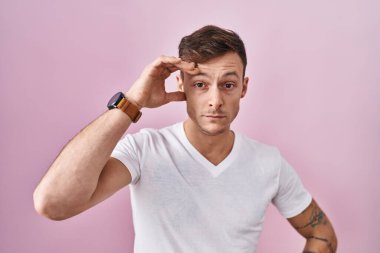 Pembe arka planda duran beyaz bir adam. Alnındaki bir sorun yüzünden endişeli ve stresli. Kriz için endişeli. 