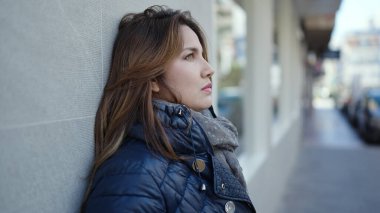 Young beautiful hispanic woman looking to the side with serious expression at street