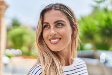 Young blonde woman smiling confident looking to the side at park
