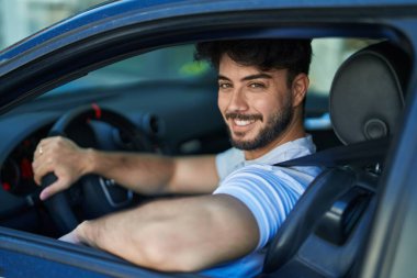 Young hispanic man smiling confident driving car at street