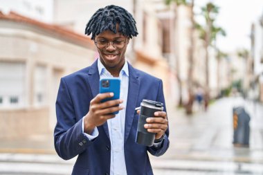 Afro-Amerikalı yönetici akıllı telefon kullanıyor. Sokakta kahve içiyor.