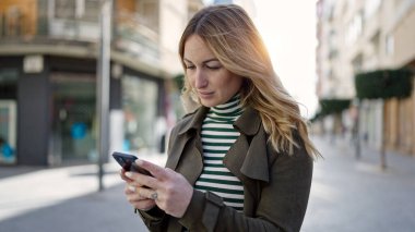 Sokakta akıllı telefon kullanan güzel bir İspanyol kadın.
