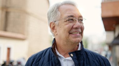 Orta yaşlı, gri saçlı, kendine güveni olan bir adam.