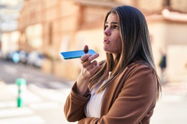 Genç ve güzel İspanyol bir kadın akıllı telefonda konuşuyor. Sokakta ciddi bir ifadeyle.